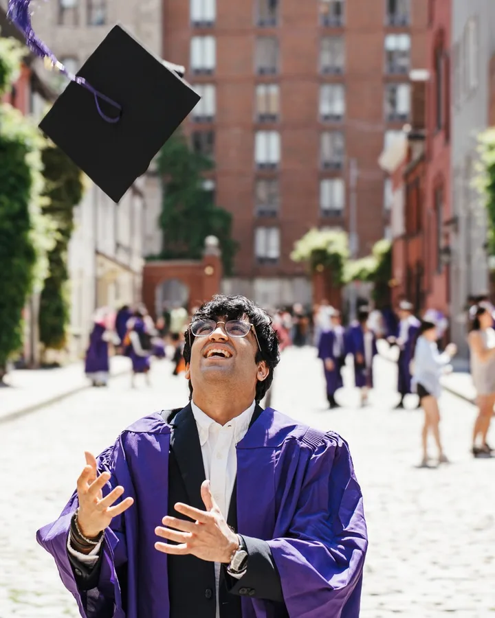 Uday Sapra at NYU graduation, cap in the air